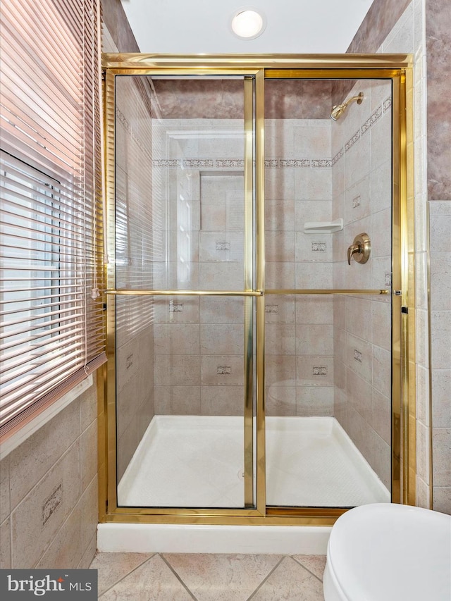 bathroom featuring tile patterned floors, a shower stall, and toilet