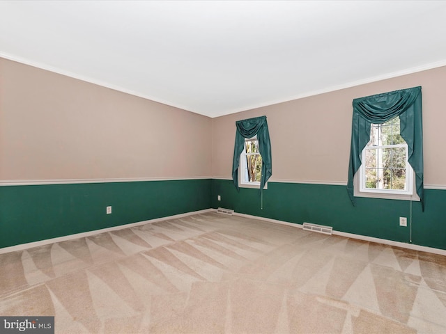 carpeted spare room with crown molding, baseboards, and visible vents