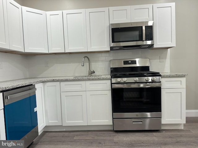 kitchen featuring a sink, wood finished floors, white cabinetry, and stainless steel appliances