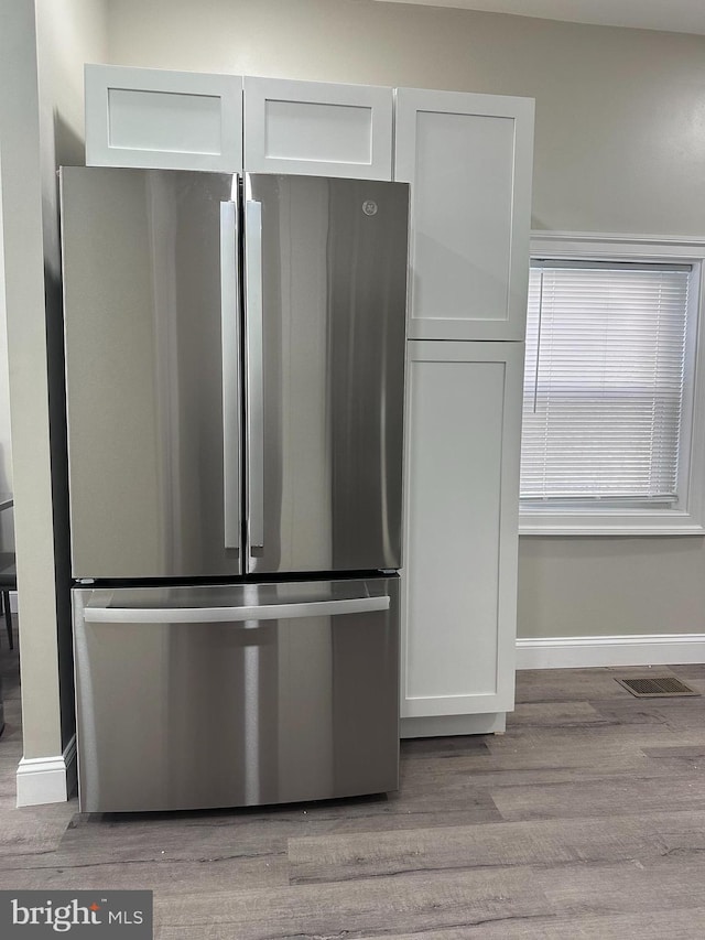 interior space featuring baseboards, visible vents, freestanding refrigerator, white cabinetry, and light wood-type flooring