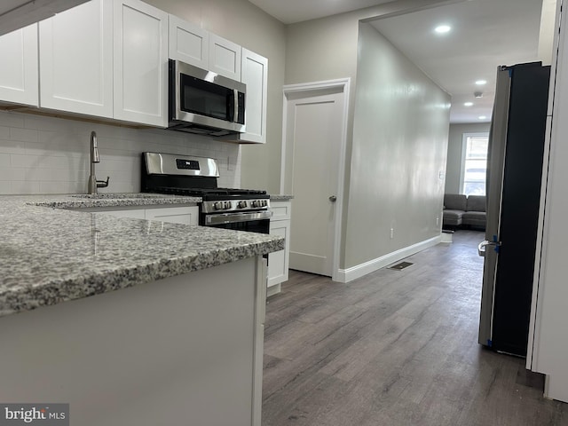 kitchen featuring visible vents, backsplash, light wood-type flooring, white cabinets, and stainless steel appliances