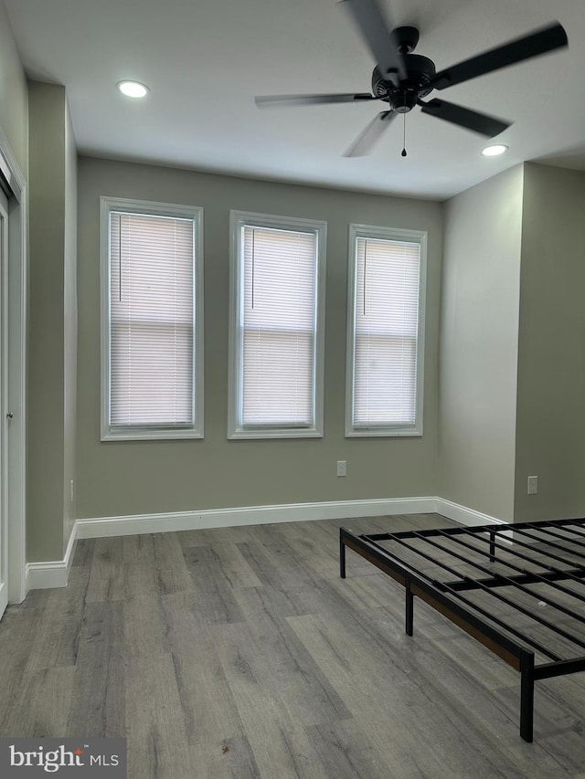 unfurnished bedroom featuring recessed lighting, wood finished floors, and baseboards