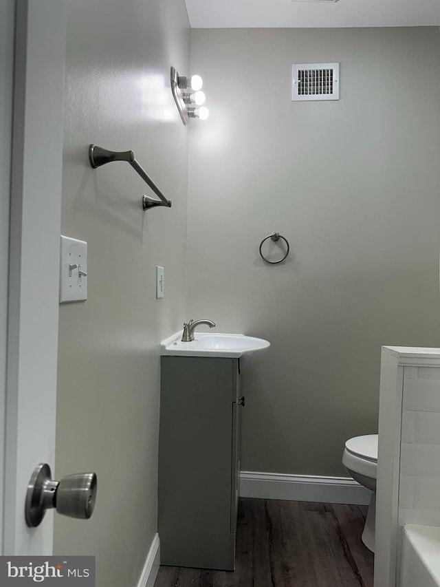 bathroom with visible vents, baseboards, toilet, and wood finished floors