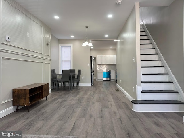 interior space featuring baseboards, wood finished floors, a chandelier, and stairs