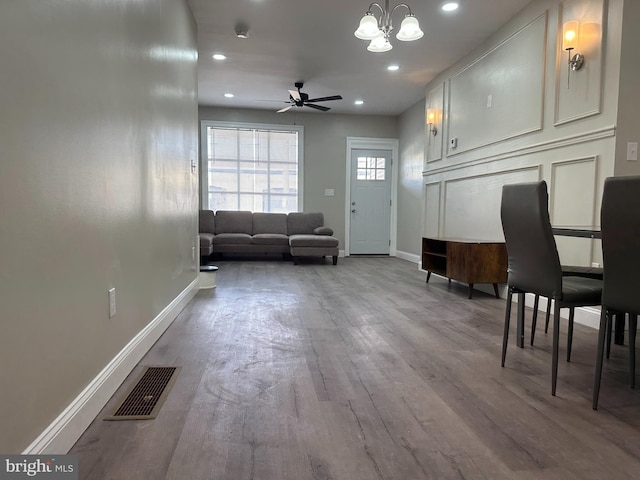 living room featuring wood finished floors, visible vents, baseboards, recessed lighting, and ceiling fan with notable chandelier