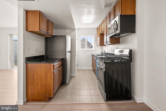 kitchen with dark countertops, visible vents, appliances with stainless steel finishes, and brown cabinets