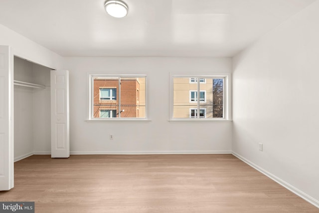 unfurnished bedroom with light wood-type flooring, baseboards, and a closet