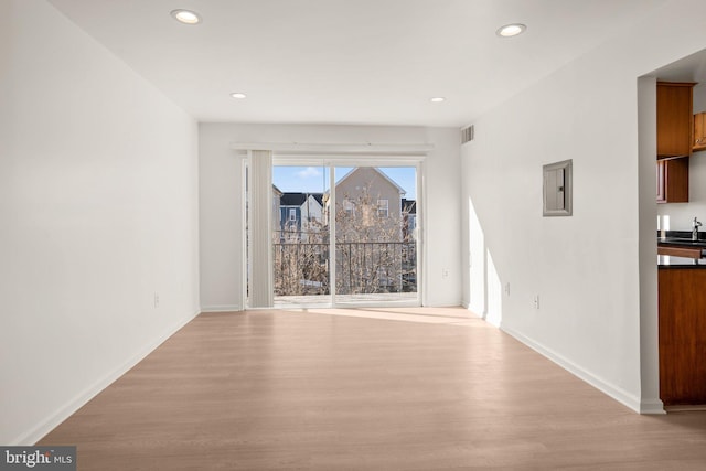 unfurnished dining area with recessed lighting, baseboards, light wood-style floors, and a sink