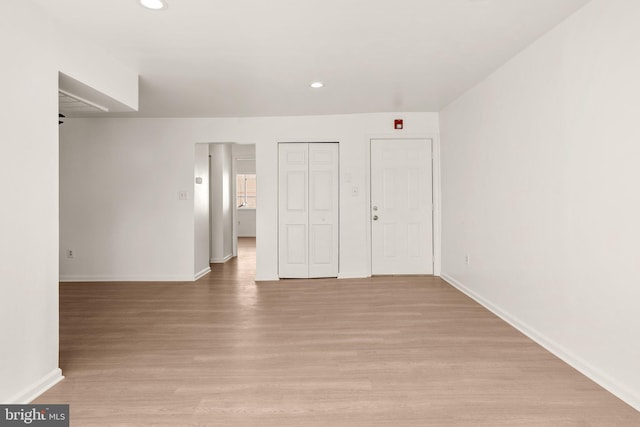 unfurnished bedroom with a closet, recessed lighting, baseboards, and light wood-style floors