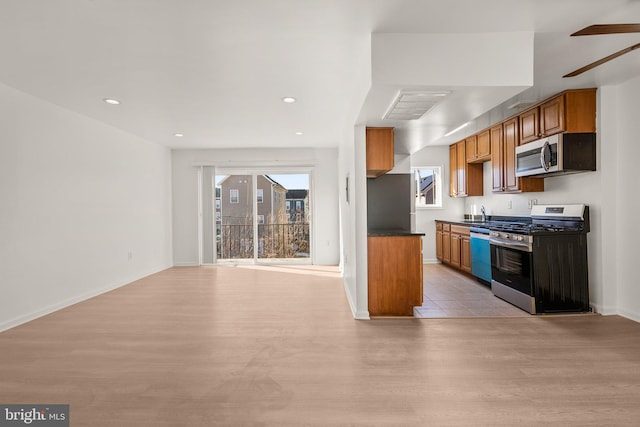 kitchen featuring dark countertops, open floor plan, stainless steel appliances, and light wood-style floors