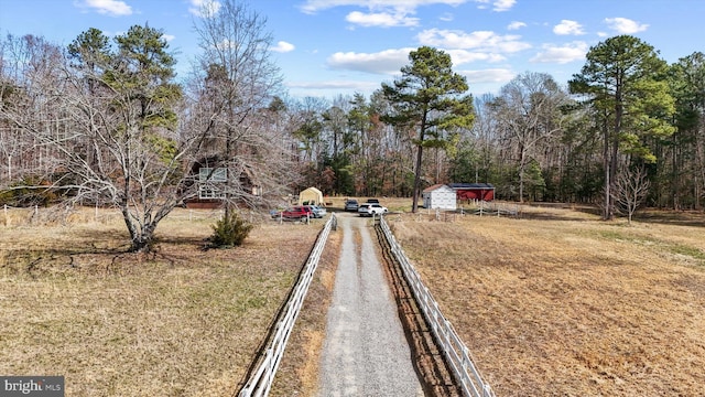 view of street with gravel driveway and a forest view