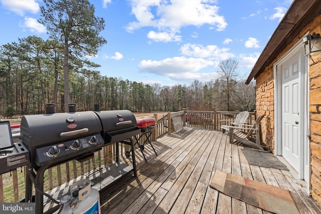 deck with grilling area and a view of trees