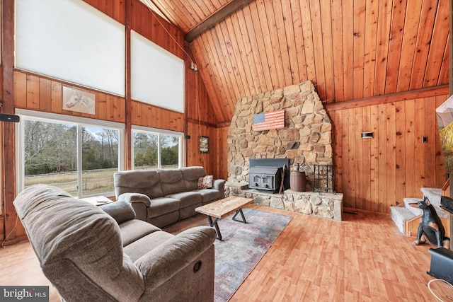 living area with wooden walls, wood finished floors, a wood stove, wooden ceiling, and beamed ceiling