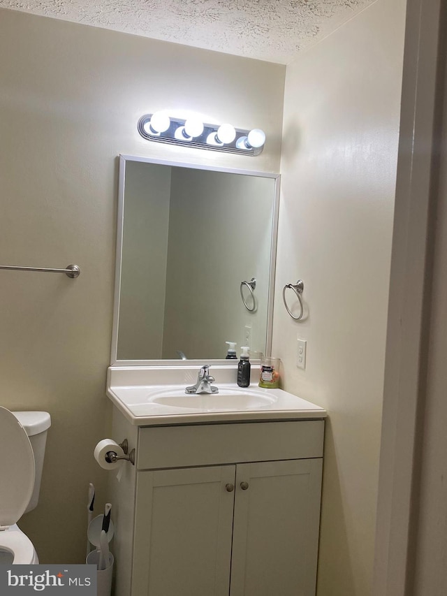 bathroom with vanity, toilet, and a textured ceiling