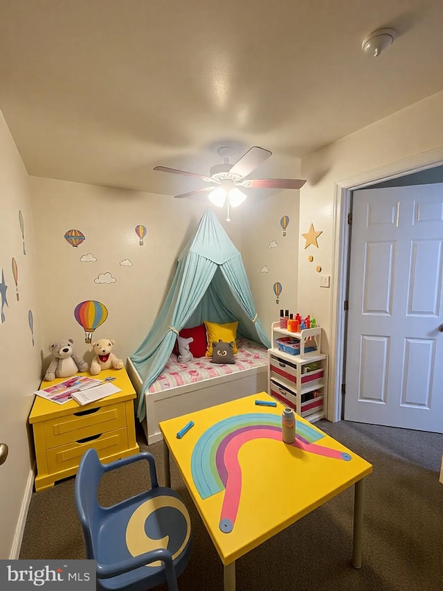 rec room featuring baseboards, ceiling fan, and dark colored carpet