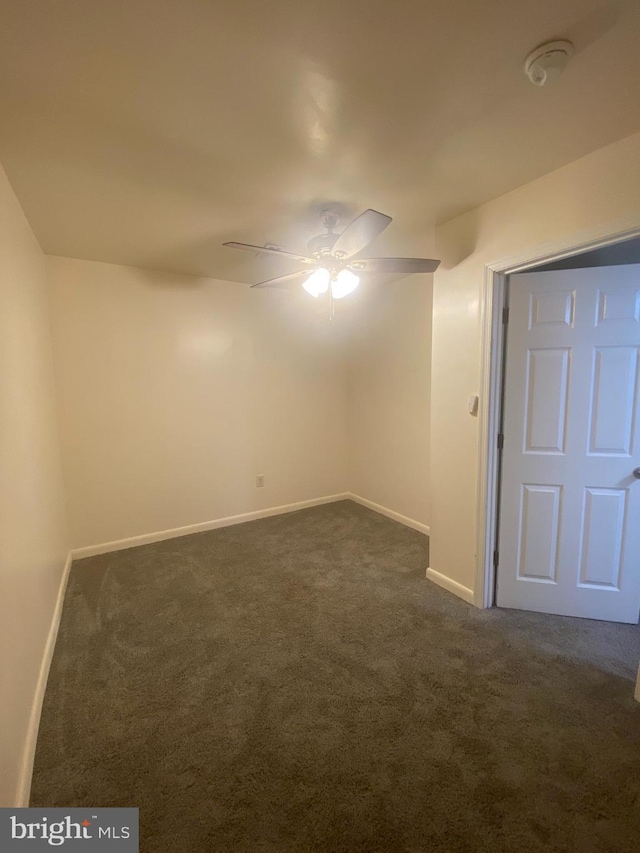 interior space featuring baseboards, dark carpet, and ceiling fan