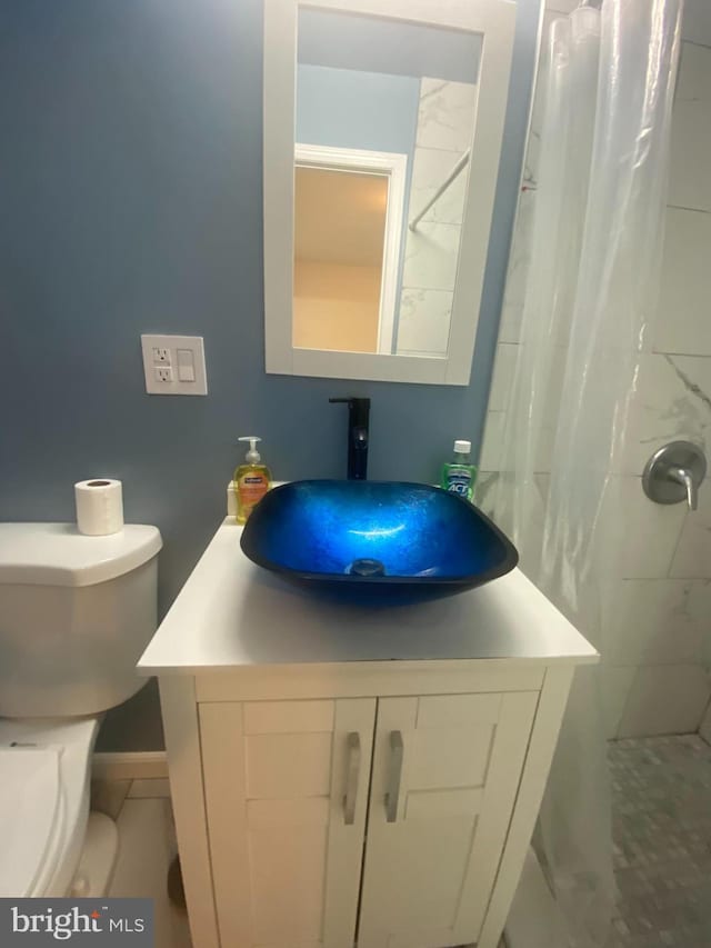 full bath with toilet, vanity, and a tile shower