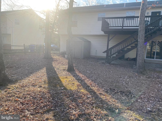 back of property featuring an outbuilding, a wooden deck, a storage unit, and stairs