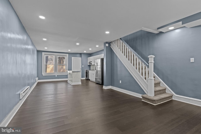 unfurnished living room with dark wood-style floors, stairway, a baseboard heating unit, and baseboards