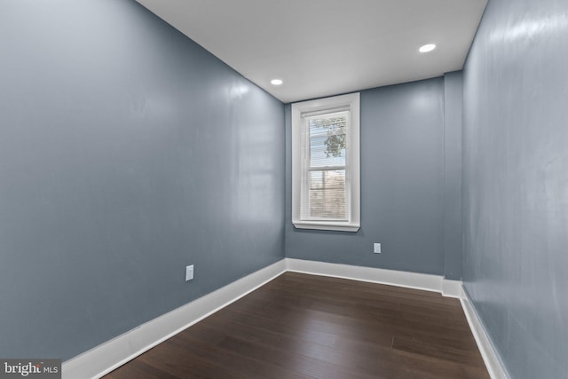 empty room with dark wood finished floors, recessed lighting, and baseboards