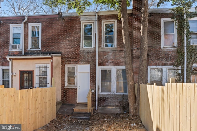 view of property with fence, brick siding, and entry steps