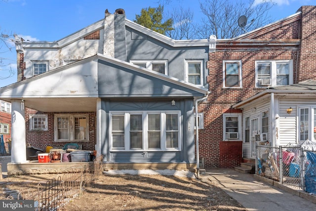 rear view of house featuring cooling unit, fence, brick siding, and entry steps