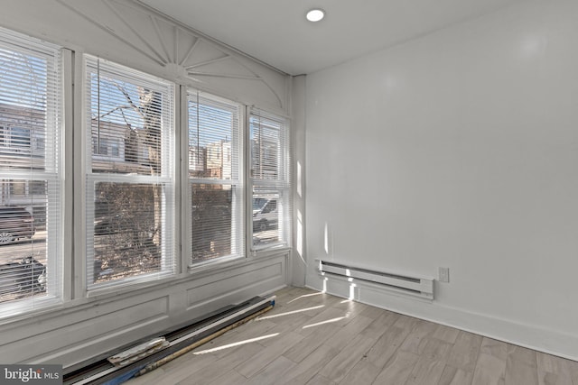 spare room with baseboard heating, recessed lighting, light wood-type flooring, and baseboards