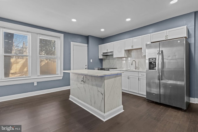 kitchen with under cabinet range hood, white cabinetry, stainless steel appliances, and a sink