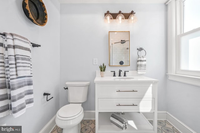 bathroom featuring baseboards, plenty of natural light, toilet, and vanity