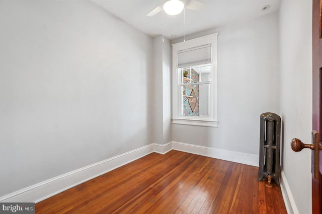 unfurnished room with baseboards, radiator heating unit, ceiling fan, and hardwood / wood-style flooring