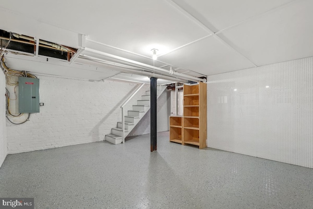 finished basement featuring electric panel, brick wall, and stairs