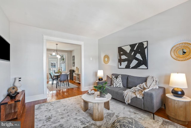 living area featuring a chandelier, baseboards, and wood finished floors