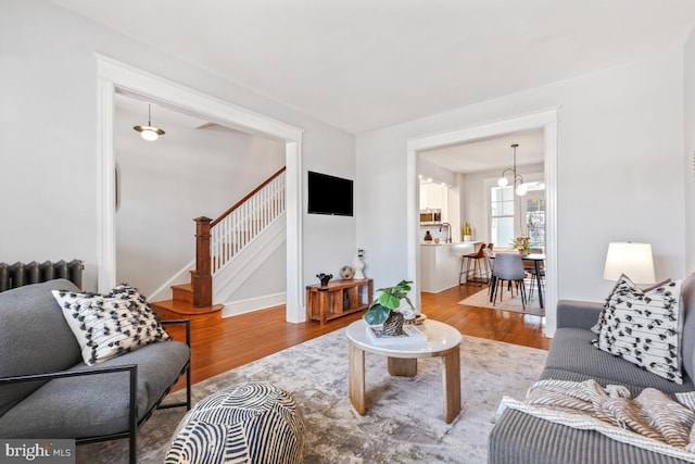 living room featuring stairs, radiator, wood finished floors, and baseboards