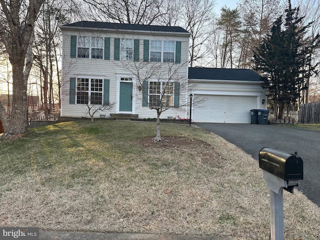 colonial home with driveway, entry steps, fence, a front yard, and a garage