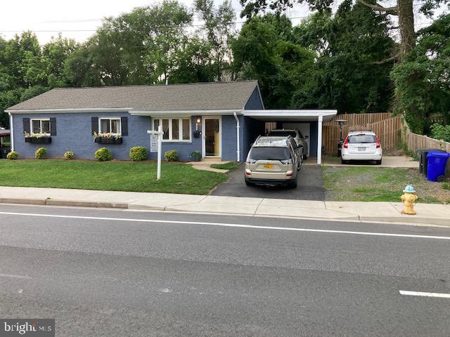 single story home with an attached carport, concrete driveway, fence, and a front lawn