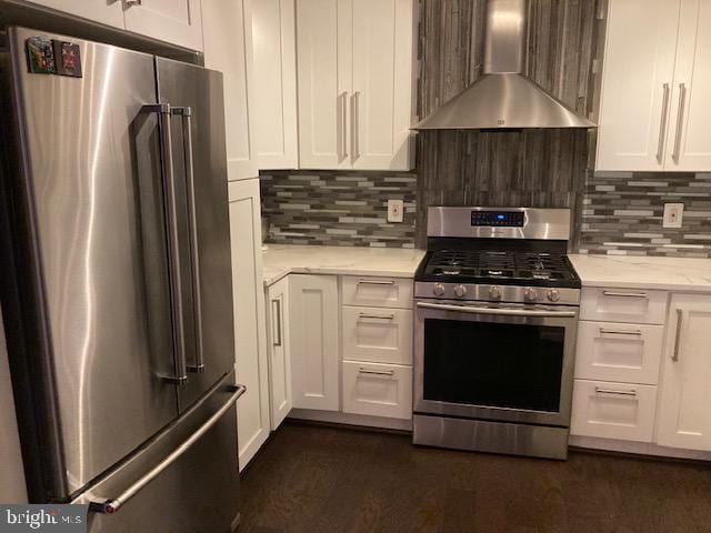 kitchen featuring decorative backsplash, white cabinets, wall chimney exhaust hood, and stainless steel appliances