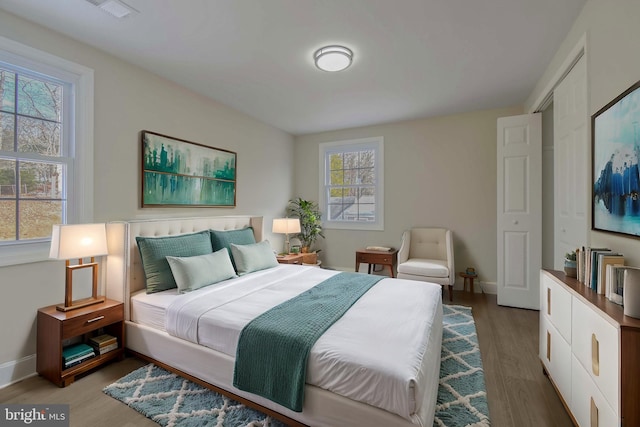 bedroom featuring visible vents, baseboards, and wood finished floors