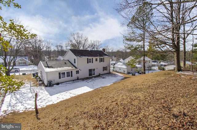 snow covered property with a chimney and central AC