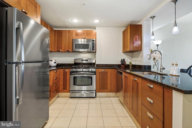 kitchen featuring a peninsula, light tile patterned flooring, a sink, stainless steel appliances, and brown cabinets