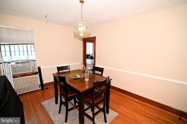 dining space with baseboards, a chandelier, radiator heating unit, cooling unit, and wood-type flooring