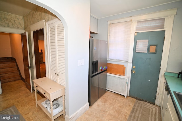 kitchen with baseboards, stainless steel fridge, arched walkways, and radiator heating unit