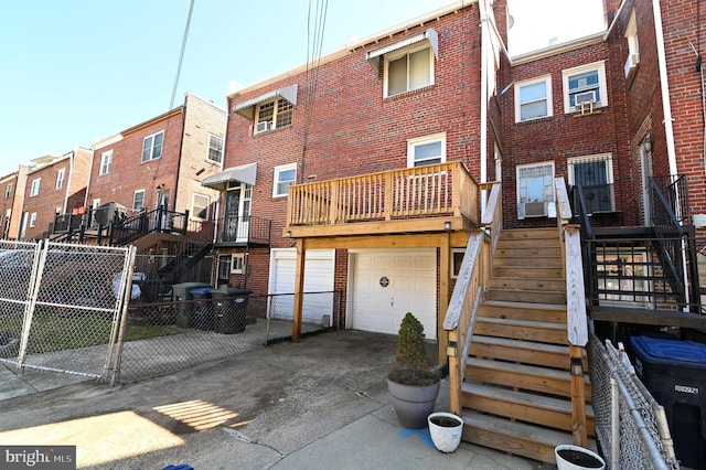 rear view of property featuring brick siding, stairway, an attached garage, and driveway