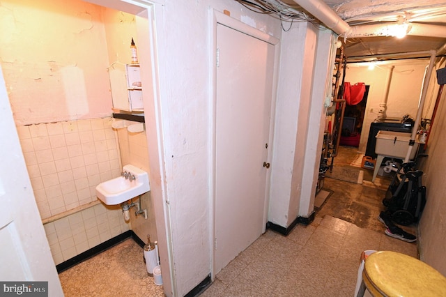 interior space with tile patterned floors, tile walls, and a sink