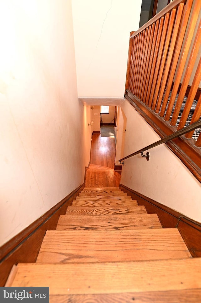 staircase featuring wood finished floors and baseboards