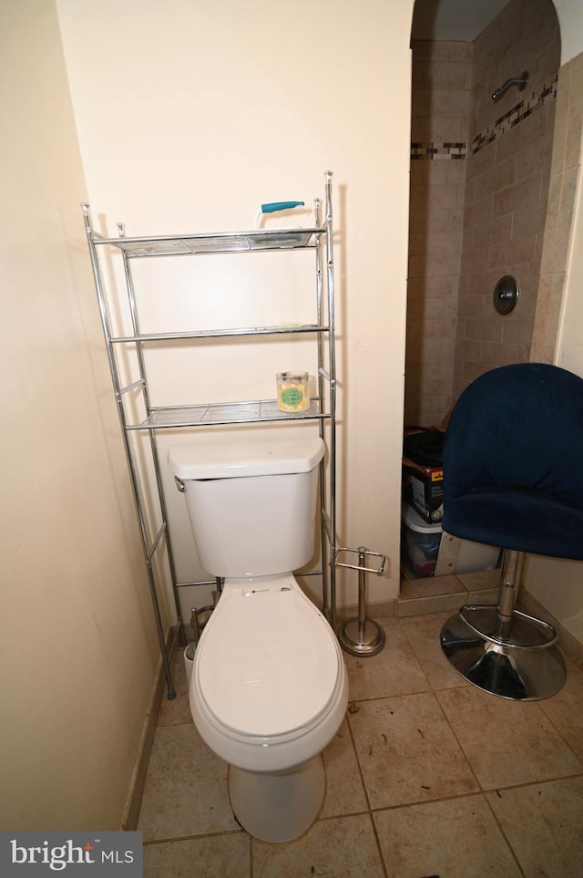 full bathroom featuring baseboards, tiled shower, toilet, and tile patterned flooring