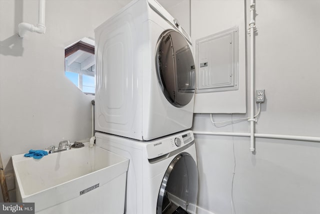 washroom with laundry area, stacked washer / dryer, electric panel, and a sink