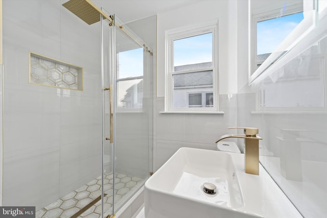 full bath with a shower stall, tile walls, and a sink