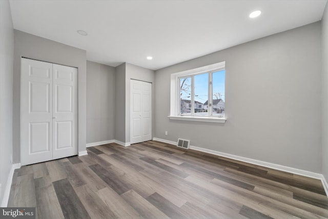 unfurnished bedroom with visible vents, recessed lighting, baseboards, and wood finished floors