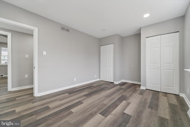 unfurnished bedroom featuring visible vents, wood finished floors, and baseboards