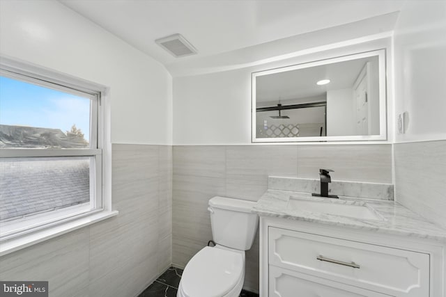 bathroom featuring visible vents, toilet, tile walls, and vanity